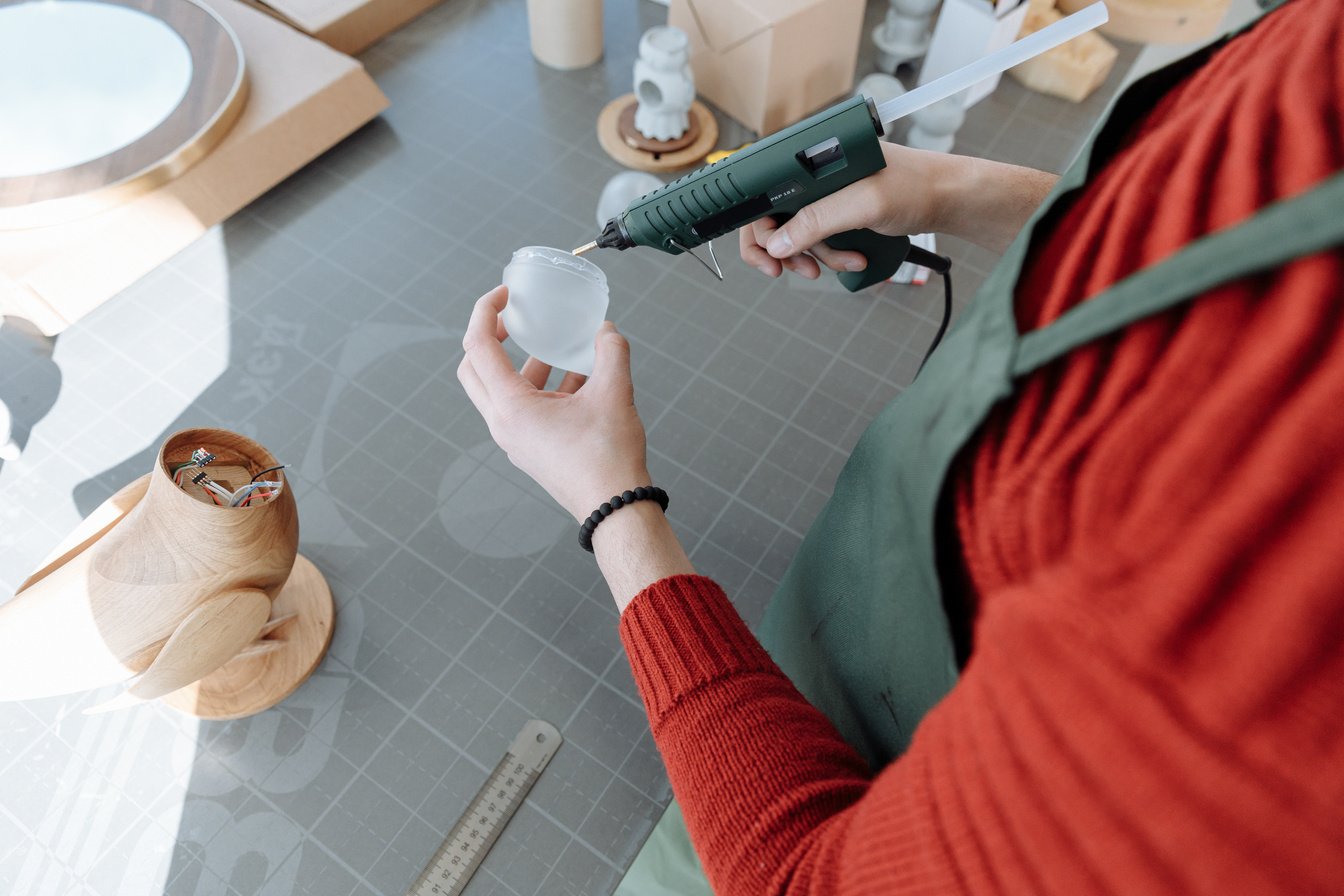 Person Putting Glue on a Smoked Glass Using Glue Gun